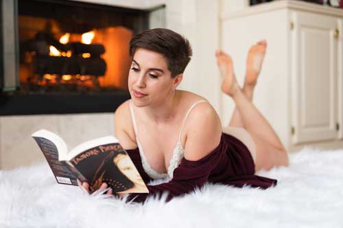 Cozy Boudoir photograph of a non-binary person reading a book in front of a fire.