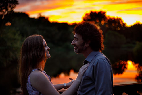 A couple gaze lovingly at each other in front of a fiery sunset at Shawnee Mission Park.