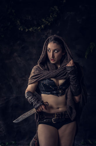 Fine art photograph of a woman in leather post-apocalyptic costume with a machete, looking to the side suspiciously.