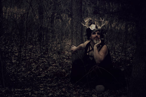 Fantasy photograph of a man in a horned floral headdress in the woods.