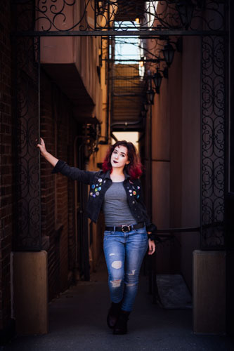 A young woman poses in an alleyway