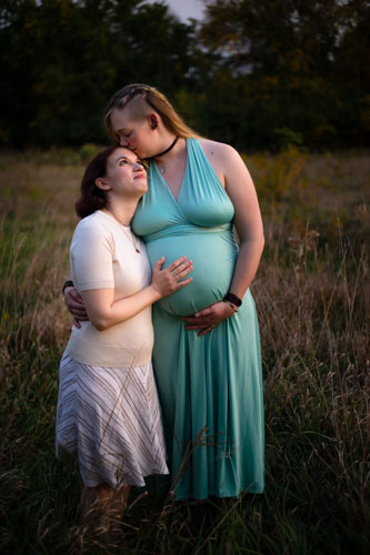 A pregnant woman and her partner hold her belly and gaze lovingly at each other