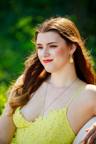 A beautiful young woman in a yellow dress smiles away from the camera