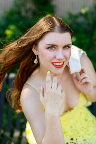 A woman in a yellow dress leans toward the camera and smiles