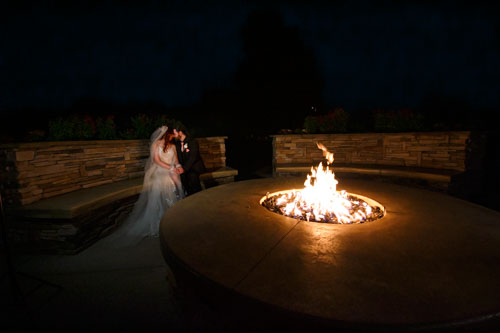 Bride and groom sharing a quiet intimate moment by a firepit.