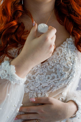 A closeup of the bride holding her necklace up for display