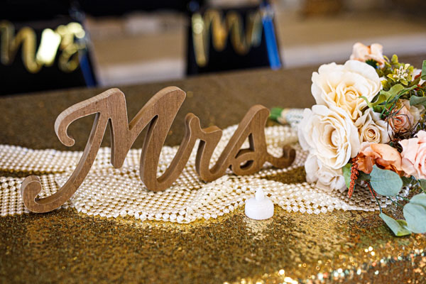 A Mrs sign and a bouquet of flowers decorate the bride and grooms' table