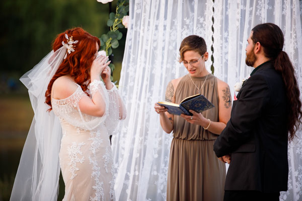 A emotional bride and groom stand at the alter of an outdoor wedding.
