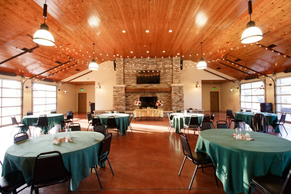 A picture of the inside of a wedding venue decorated with candles, lights, and emerald green tableclothes